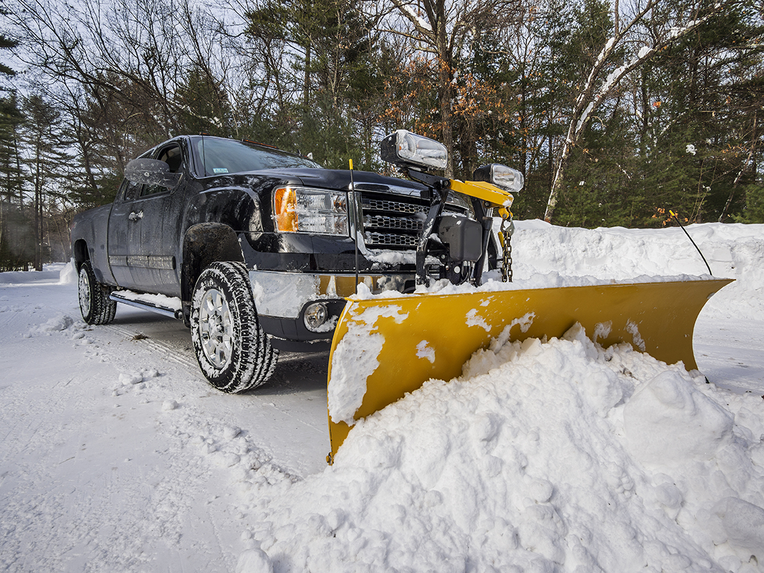Snow plow truck clearing deep snow from a property
